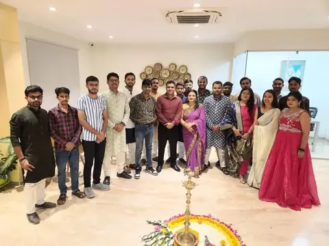 Team gathered around a decorated lamp for a Diwali celebration at the office