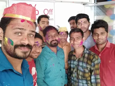 Team members with colored powder on their faces celebrating Holi at the office