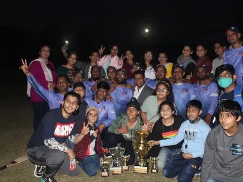 Cricket team and their families celebrating with trophies after the Lions Premier League match at night