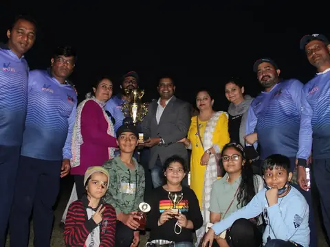 The winning cricket team holding their championship trophy with family members at night