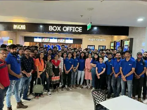 Team in matching blue t-shirts gathered at a cinema box office for a group outing