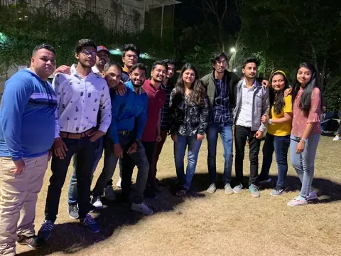 Team members posing together outdoors on a lawn in the evening
