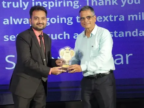Team member receiving an appreciation trophy on stage at the TechVersary event