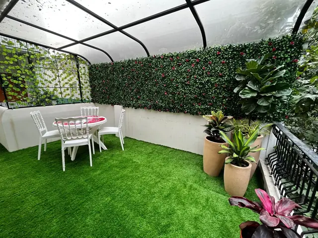 Rooftop garden terrace at Rays EdTech with artificial grass, seating, and a green plant wall